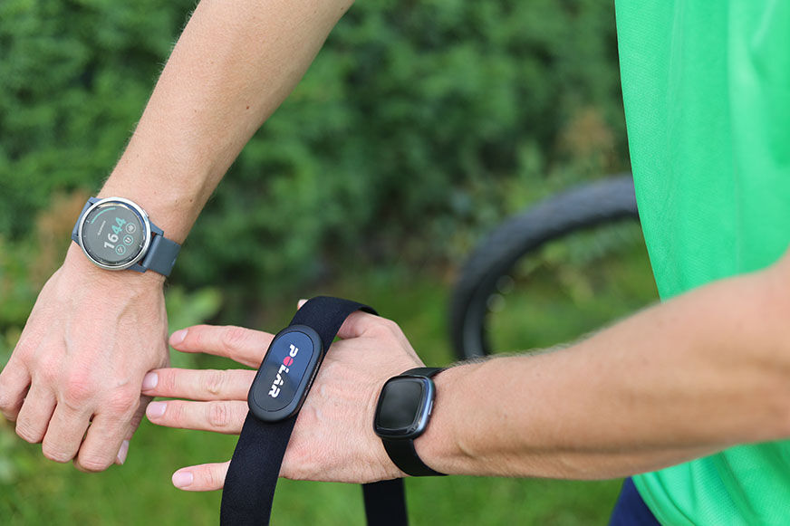 Man sieht die Garmin vivoactive 4, die Fitbit Versa 4 und den Polar H10 Brustgurt. 